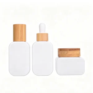 Empty glass skincare packaging set with bamboo cap – pearl lotion bottle, dropper bottle, and cream jar